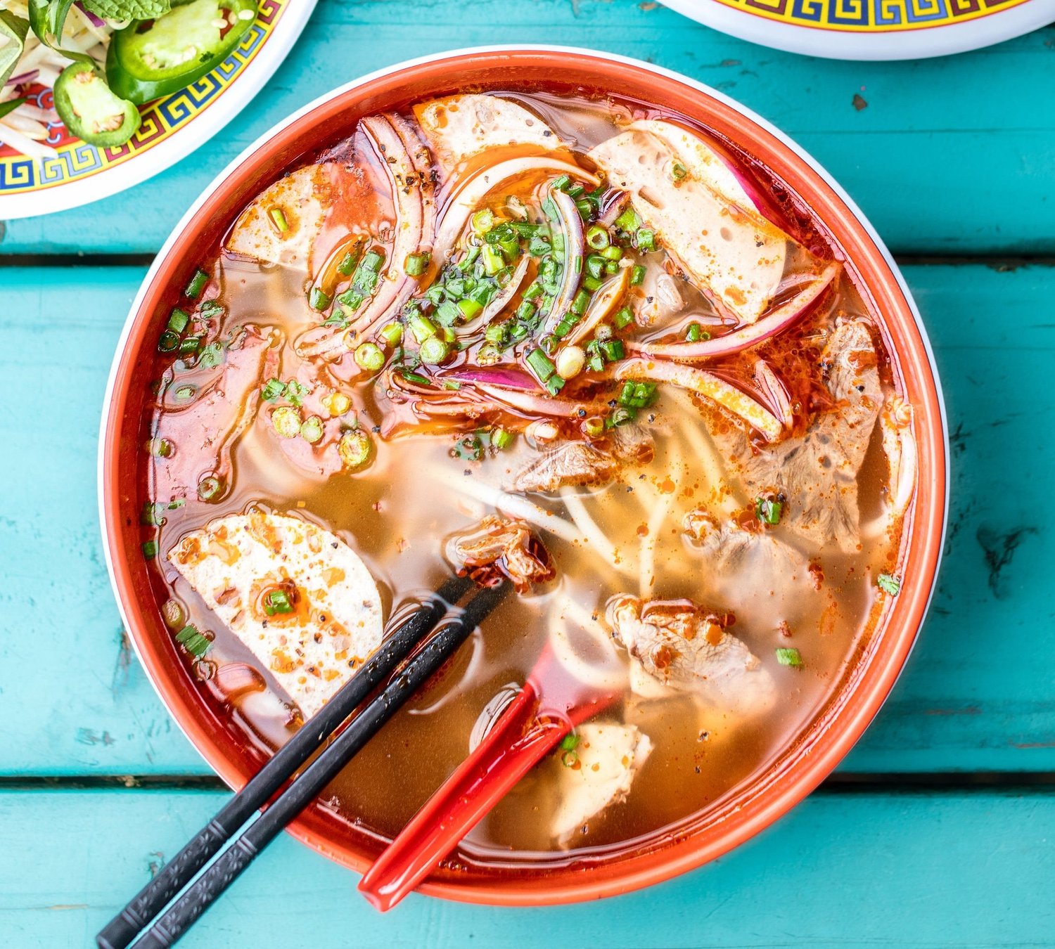 A steaming bowl of Vietnamese noodle soup with herbs and beef